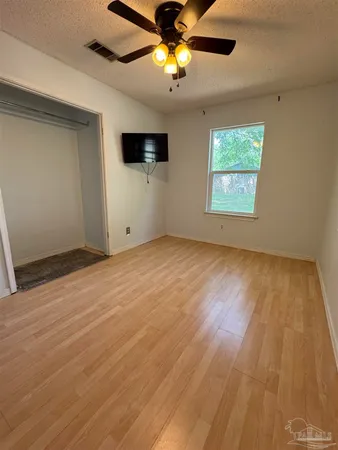 a view of empty room with wooden floor and fan