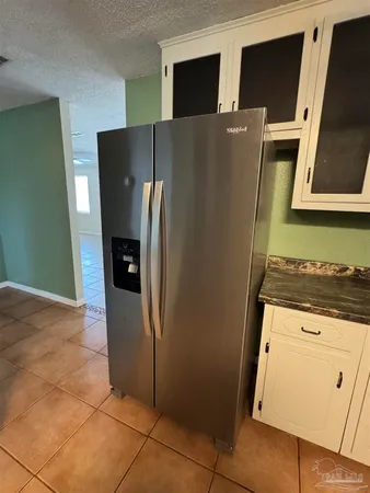 a view of a refrigerator in kitchen and an empty room