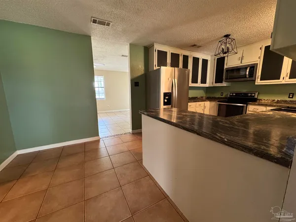 a kitchen with granite countertop a refrigerator and a stove top oven
