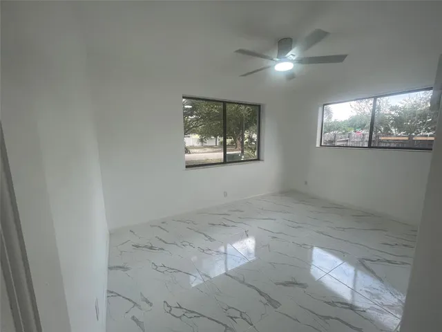 an empty room with windows and ceiling fan