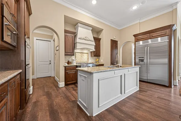 a kitchen with stainless steel appliances granite countertop a refrigerator a stove and a sink with wooden floor