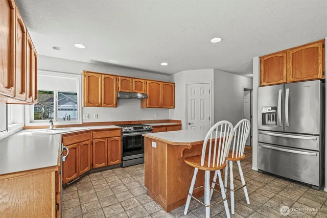 a kitchen with stainless steel appliances granite countertop a stove a sink a refrigerator and island