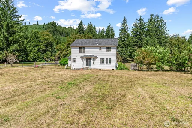a view of a house with a big yard and large trees