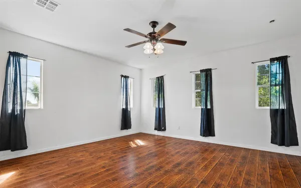 a view of empty room with wooden floor and fan
