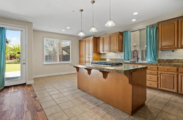 a kitchen with kitchen island granite countertop a stove a sink a center island and furniture