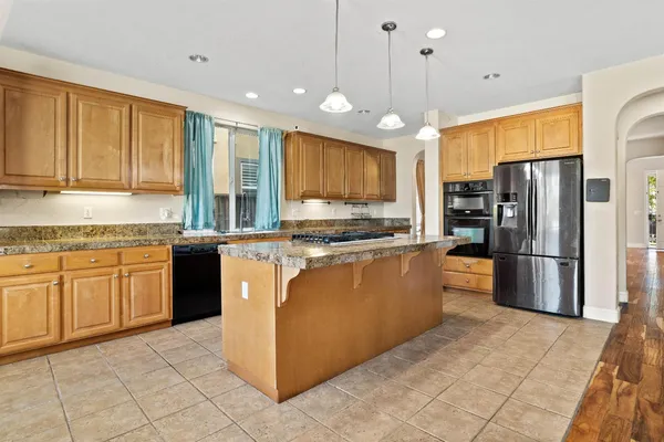 a kitchen with stainless steel appliances granite countertop a refrigerator a stove a sink and a microwave