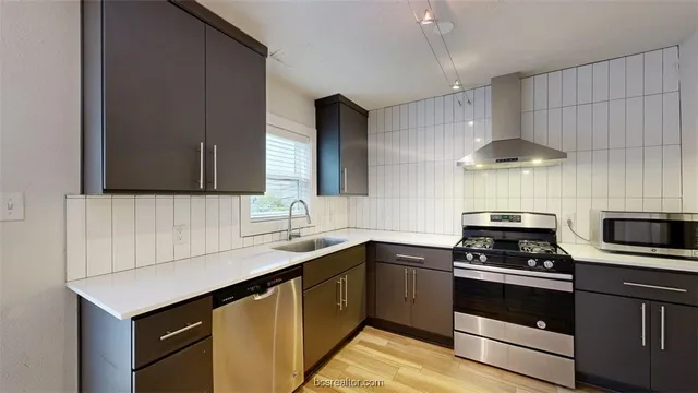 a kitchen with stainless steel appliances a sink dishwasher a stove and a refrigerator