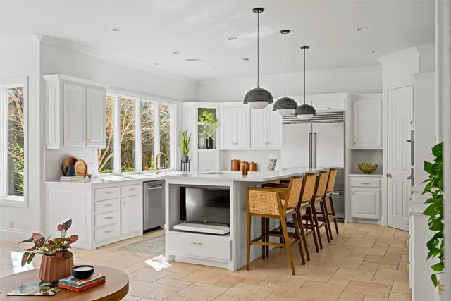 a kitchen with kitchen island a dining table chairs sink and stove