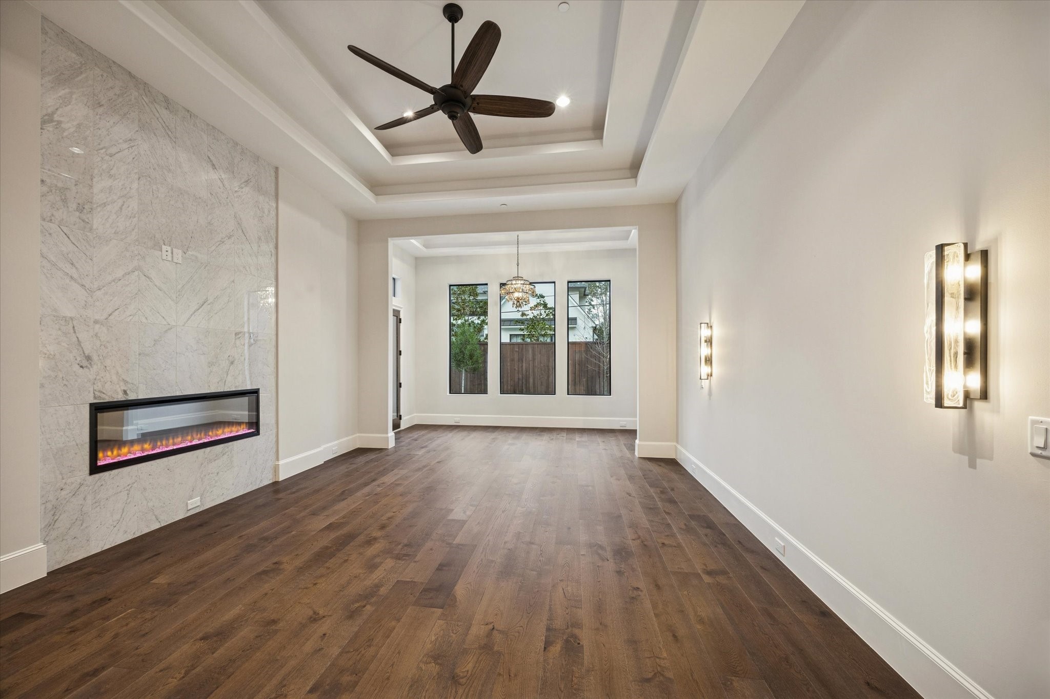 318 Knipp Road Houston, TX 77024 - Photo 10 of 32 Expansive first floor primary suite featuring tray ceilings, a sleek linear firepace, hardwood floors, with serene backyard views and private access to the pool and outdoor living spaces.
