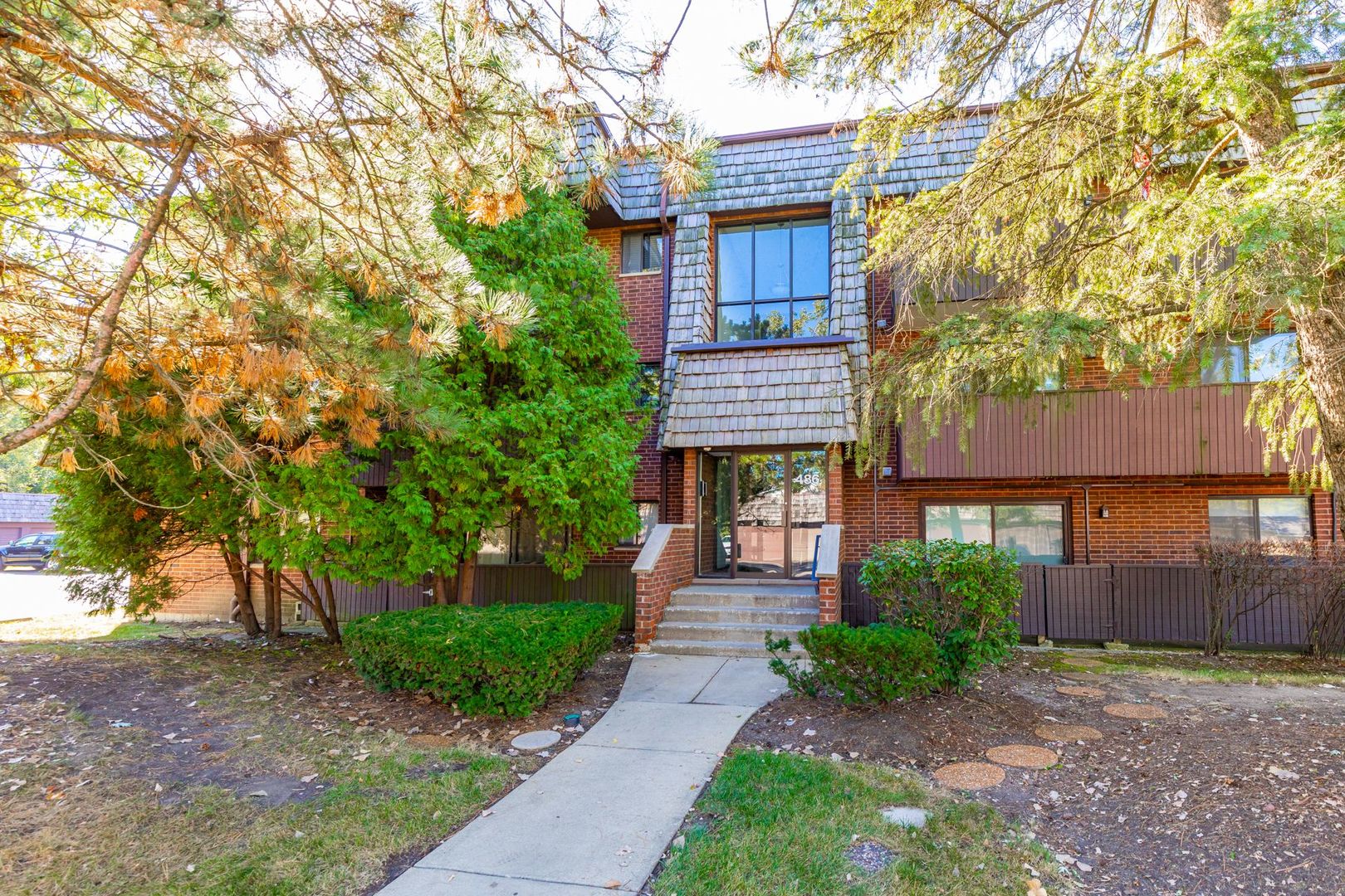 486 Timber Ridge Drive, Unit 102 Carol Stream, IL 60188 - Photo 1 of 23 a view of a brick house with a yard and large trees