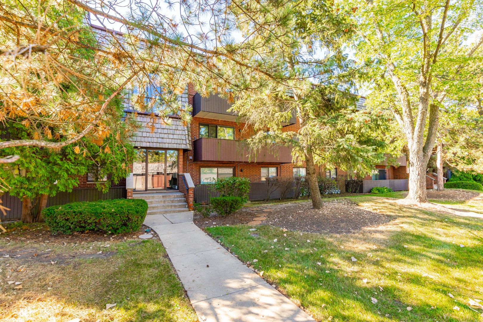 486 Timber Ridge Drive, Unit 102 Carol Stream, IL 60188 - Photo 22 of 23 a front view of a house with a yard and trees