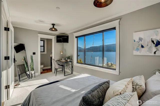 a bedroom with a bed and a large mirror next to a window