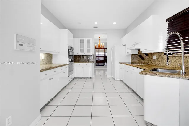 a kitchen with stainless steel appliances kitchen island granite countertop a refrigerator and a stove top oven