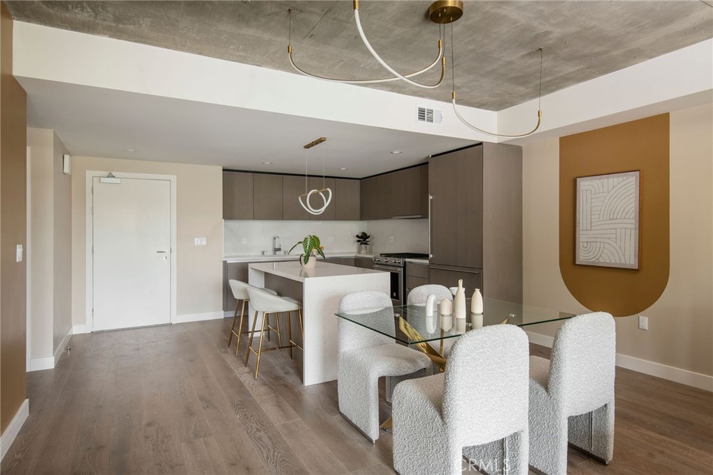 380 Cordova Street, Unit 409 Pasadena, CA 91101 - Photo 5 of 24 a room with stainless steel appliances kitchen island granite countertop a dining table chairs and a refrigerator