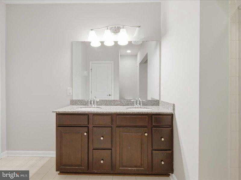 42143 Piebald Square Aldie, VA 20105 - Photo 26 of 34 a bathroom with a granite countertop sink a large mirror and a wooden cabinets