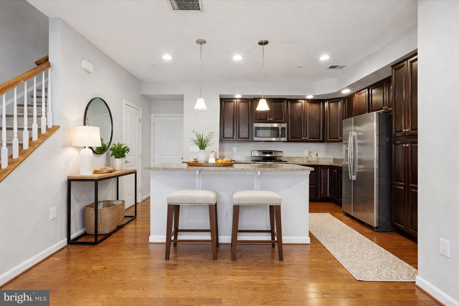 42143 Piebald Square Aldie, VA 20105 - Photo 9 of 34 a kitchen with stainless steel appliances granite countertop a stove a sink a refrigerator and a dining table with wooden floor