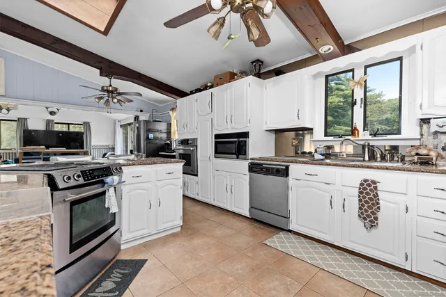 a kitchen with granite countertop a sink stainless steel appliances and white cabinets