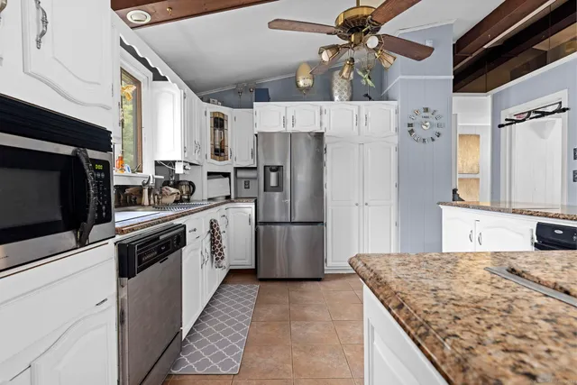 a kitchen with stainless steel appliances granite countertop a sink a stove a refrigerator a washer dryer and cabinets