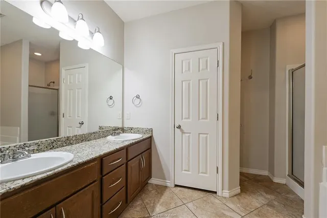 a spacious bathroom with a granite countertop sink a mirror and a shower