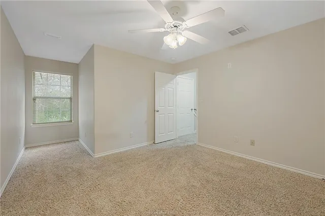 an empty room with a window and a fan