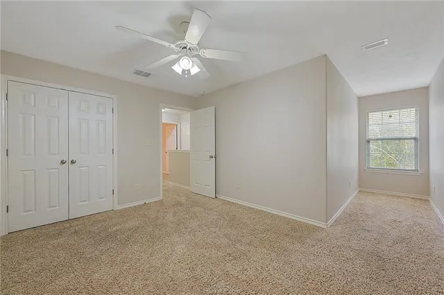 a view of an empty room with window and chandelier fan