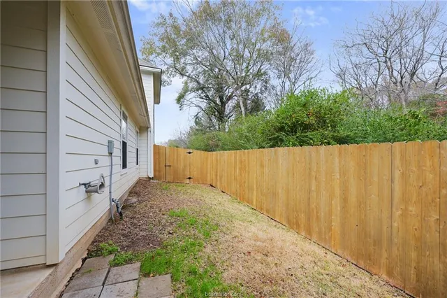 a view of a pathway of a backyard with wooden fence
