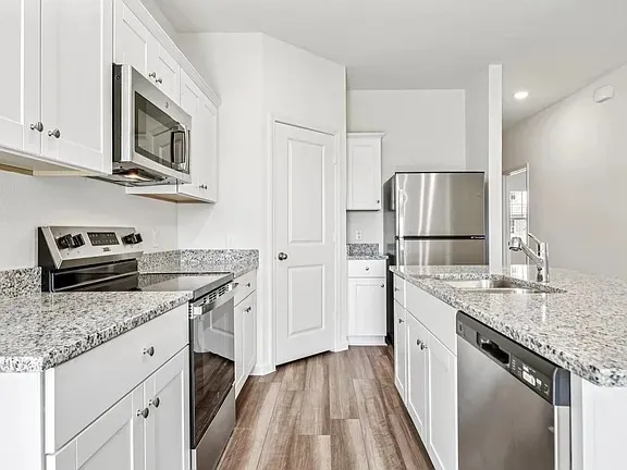 a kitchen with granite countertop a refrigerator stove and microwave