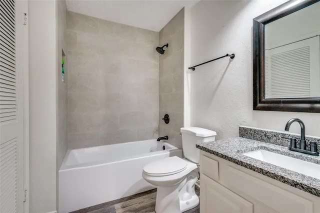a bathroom with a granite countertop toilet a sink and a bathtub
