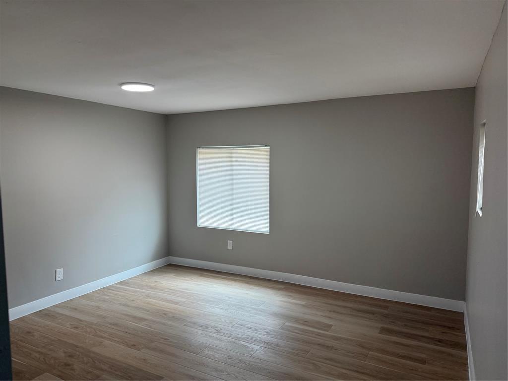 117 Aztec Way West Tawakoni, TX 75474 - Photo 11 of 12 Neutral-toned room featuring a single window with blinds, recessed ceiling lighting, wood-finish flooring, and white baseboards