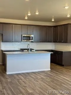 a kitchen with kitchen island granite countertop wooden cabinets a sink and a stove