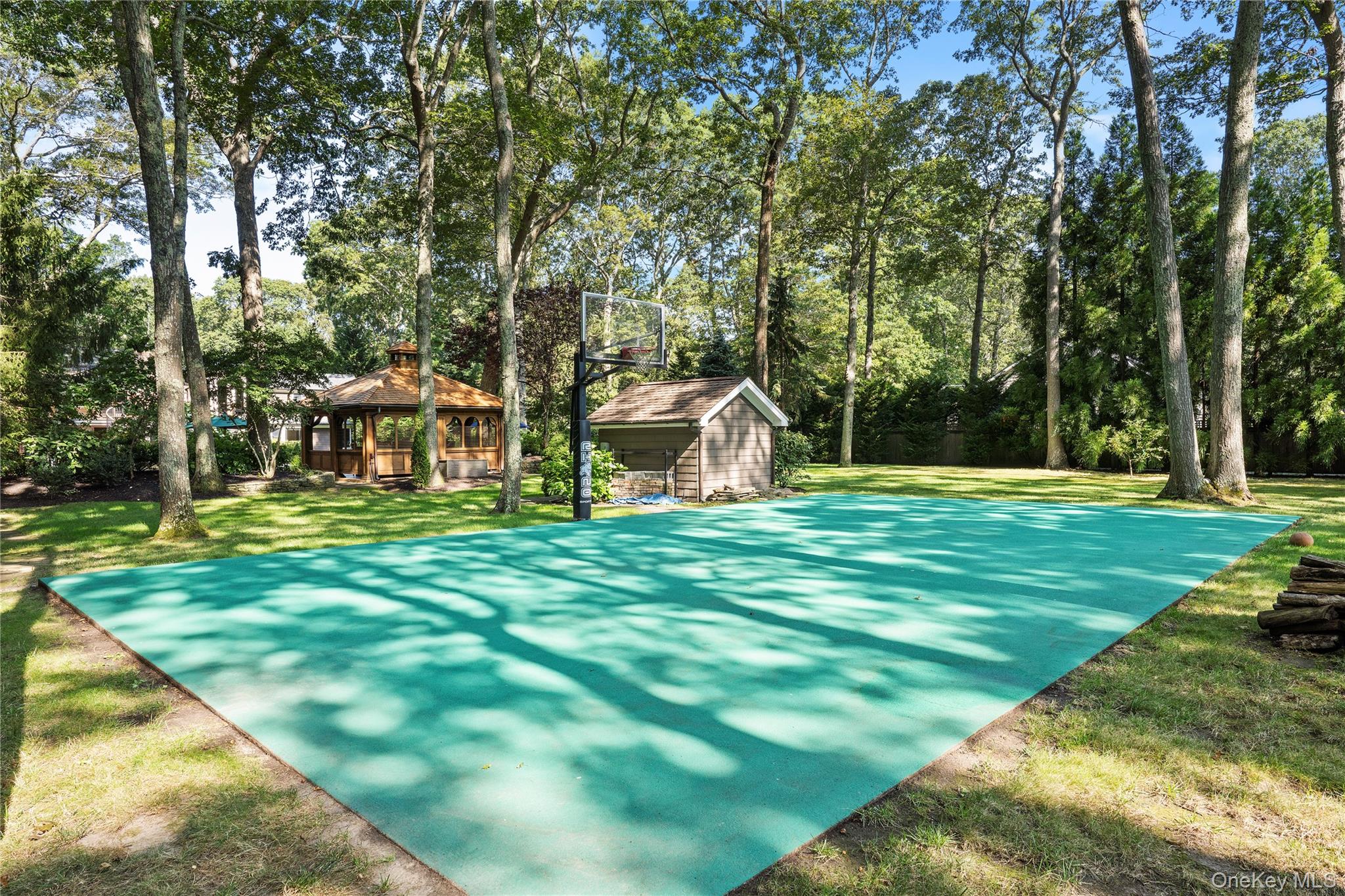 4745 North Bayview Road Southold, NY 11971 - Photo 27 of 31 View of sport court with view of wooded area, a gazebo, a yard, and basketball hoop