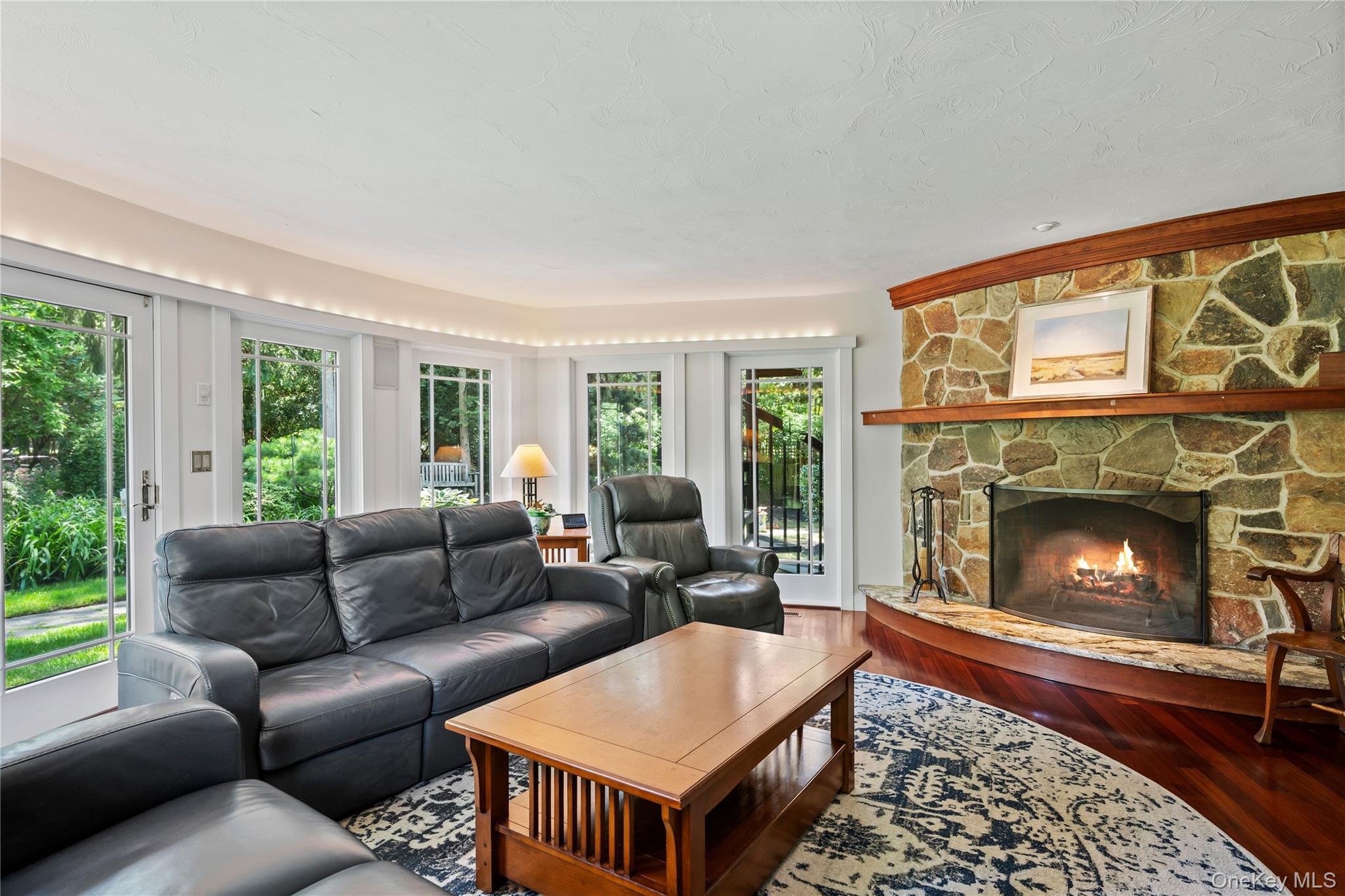 4745 North Bayview Road Southold, NY 11971 - Photo 6 of 31 Living room with a stone fireplace, wood finished floors, and a textured ceiling