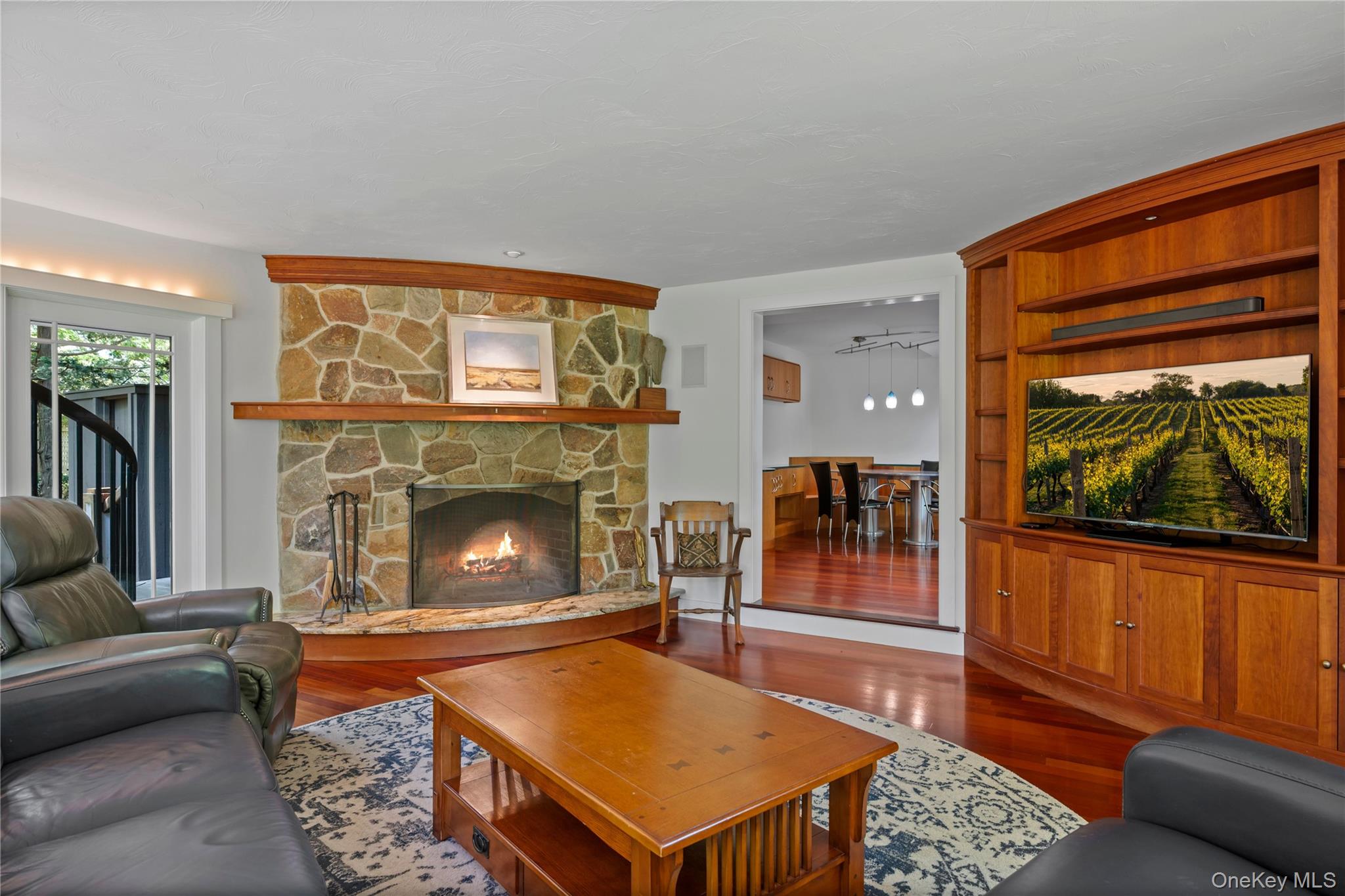 4745 North Bayview Road Southold, NY 11971 - Photo 7 of 31 Living room with a stone fireplace and dark wood-style flooring