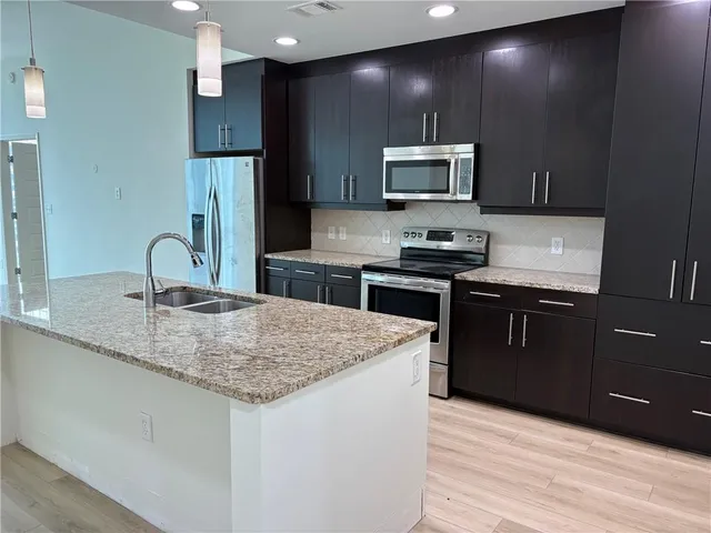 a kitchen with stainless steel appliances granite countertop a sink stove and refrigerator
