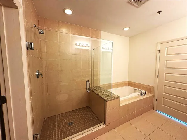 a bathroom with a tub a sink a mirror and a shower