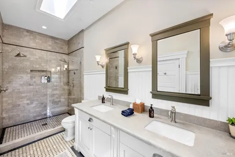 a bathroom with double vanity sink a mirror and a shower