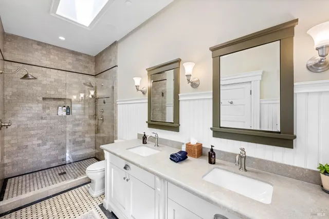 a bathroom with double vanity sink a mirror and a shower