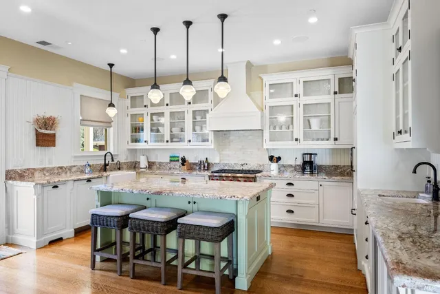 a kitchen with stainless steel appliances granite countertop a stove a sink dishwasher and white cabinets with wooden floor