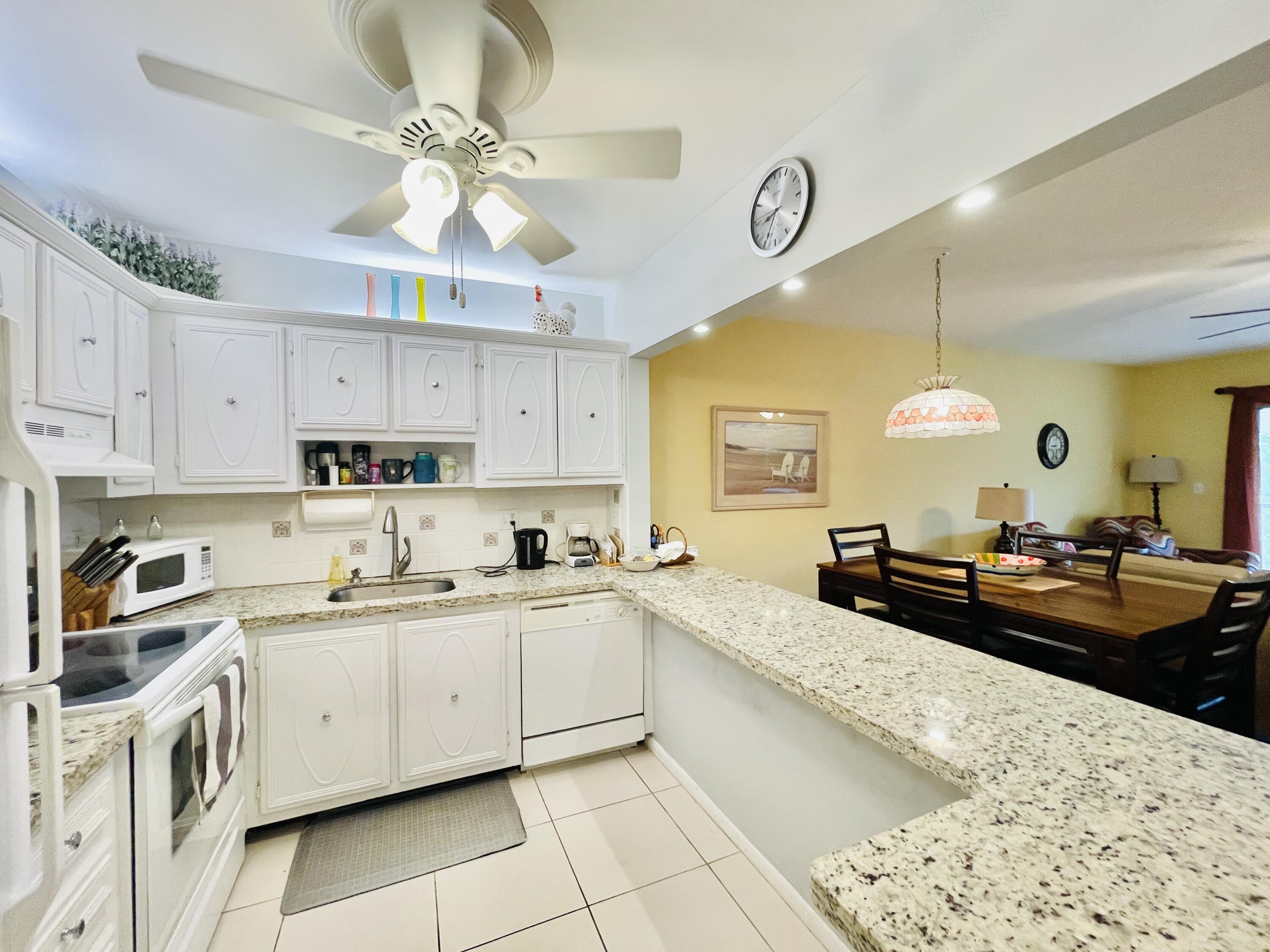 257 South Cypress Road, Unit 442 Pompano Beach, FL 33060 - Photo 5 of 37 a kitchen with a sink dishwasher a stove a dining table and chairs with wooden floor