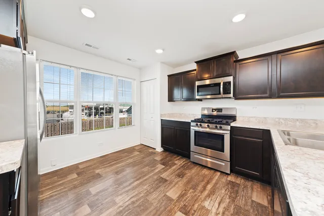 a kitchen with granite countertop a refrigerator stove and microwave