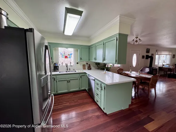 a kitchen with kitchen island granite countertop wooden floors and a refrigerator