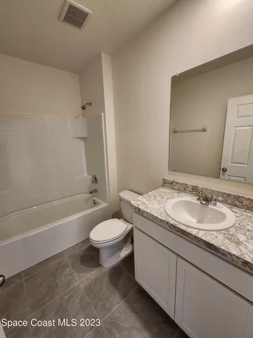 a bathroom with a granite countertop sink a toilet a mirror and bathtub