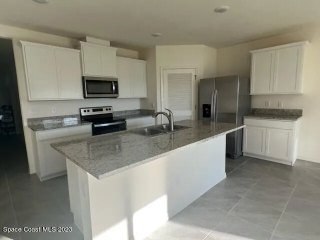 a kitchen with stainless steel appliances granite countertop a sink a stove top oven a counter space and cabinets