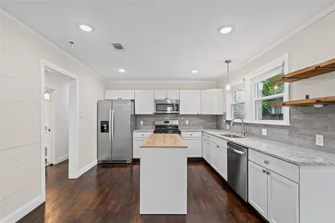 a kitchen with stainless steel appliances white cabinets and wooden floor