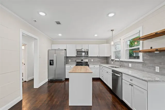 a kitchen with stainless steel appliances white cabinets and wooden floor