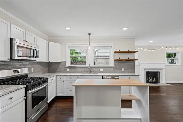 a kitchen with stainless steel appliances granite countertop a stove top oven a sink dishwasher and a refrigerator with wooden floor