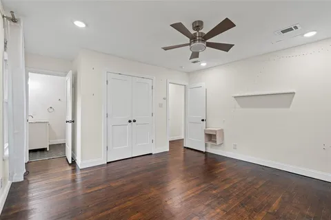 an empty room with wooden floor and a ceiling fan