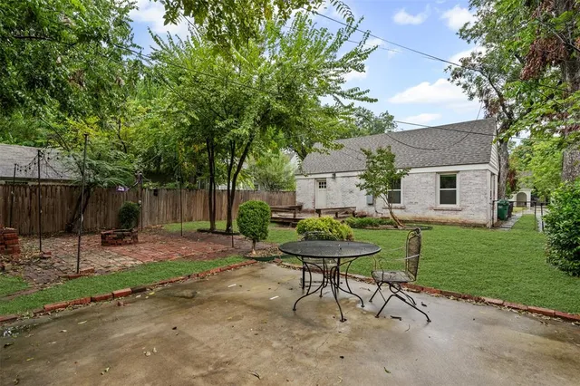 a view of a backyard with table and chairs and a barbeque with wooden fence