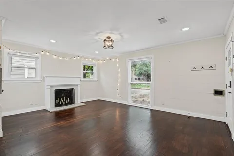 an empty room with wooden floor fireplace and windows