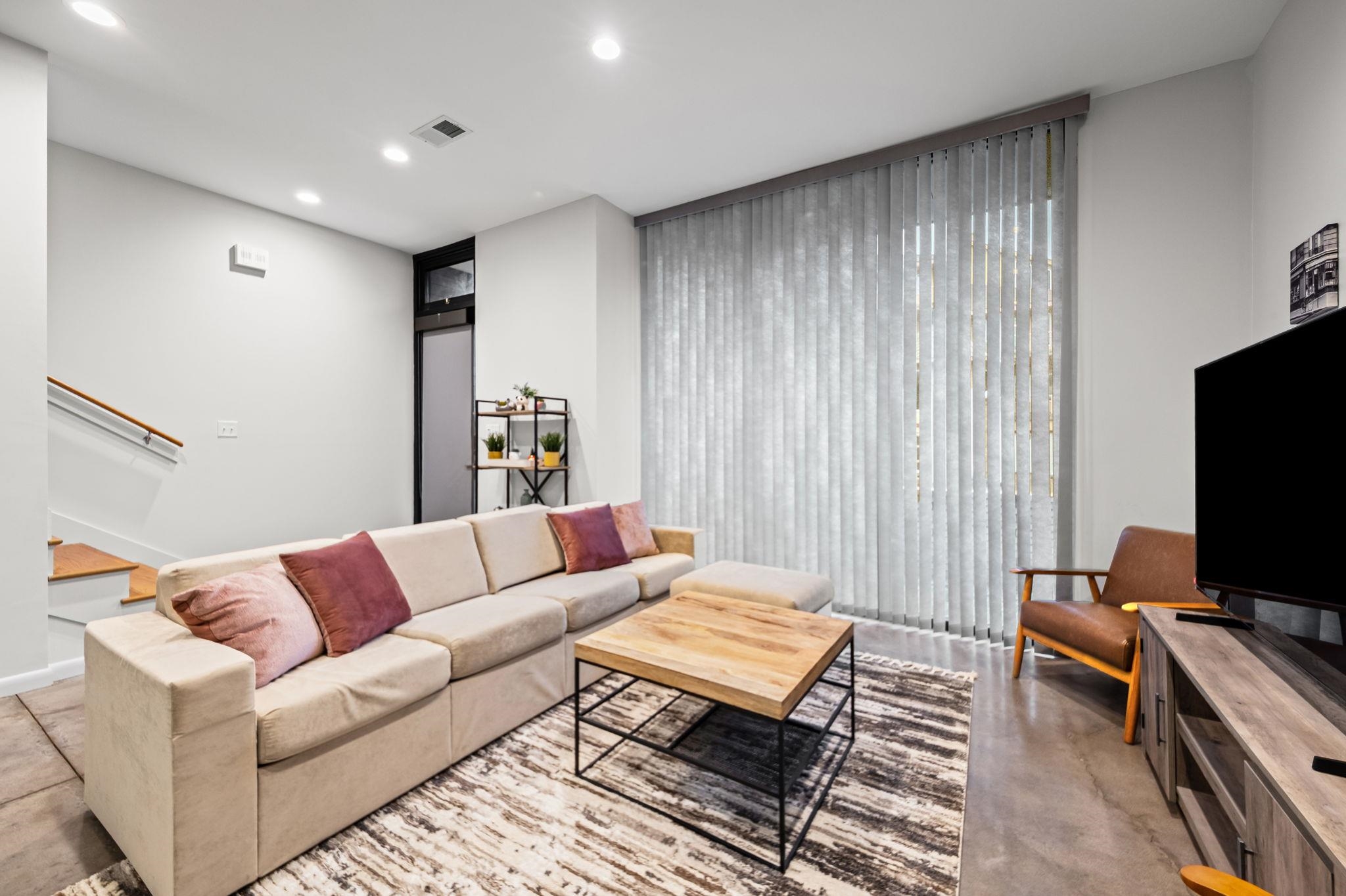 448 Tennessee Street Memphis, TN 38103 - Photo 35 of 39 Spacious living area featuring high ceilings, recessed lighting, large vertical blinds, a visible stairway with wooden handrails, and a sleek wood-finish media console